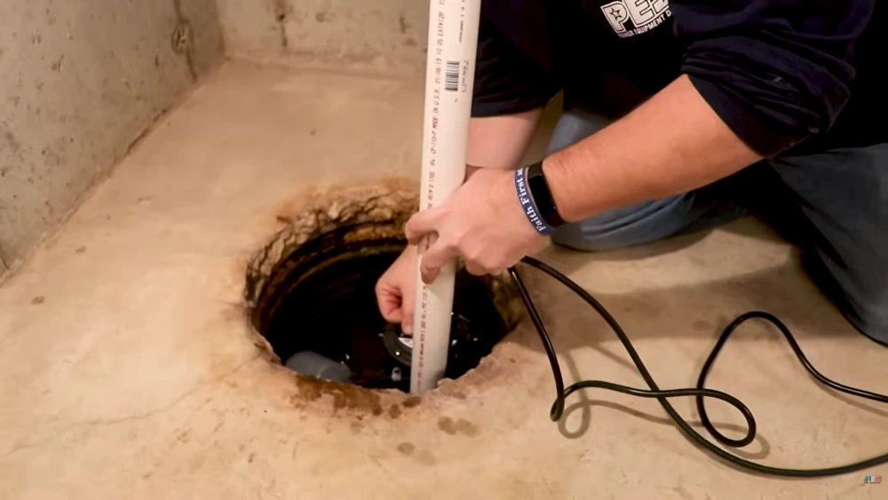 Technician installing sump pump basin in Cherry Hill basement